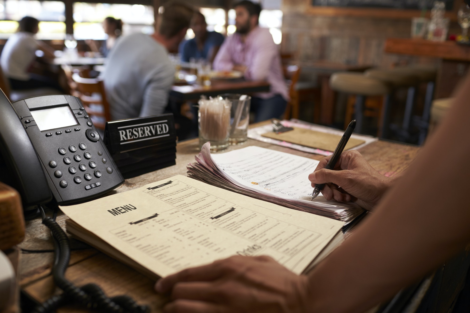 Employee at a restaurant writing down a table reservation